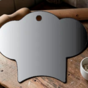 Shiny, hat-shaped mirror with a hanging hole at the top, resting on a wooden table.