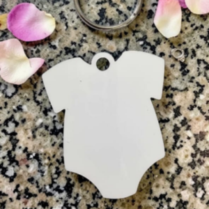 Blank white shield-shaped tag with a hanging hole, resting on a speckled granite surface among pink rose petals.