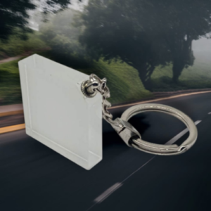 White plastic access card on a silver keyring, set against a blurred road background for emphasis on security ID badge.