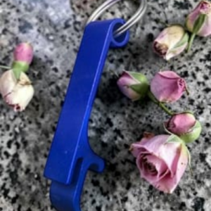 Blue plastic key tag with a metal ring lies on a speckled granite surface amid pink rosebuds.