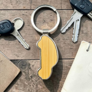 Keychain with a wooden peanut-shaped charm on a ring, surrounded by car keys on a wooden table.