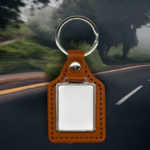 Leather keychain with a blank rectangular badge holder and a metal ring, set against a blurred road background at speed impression.