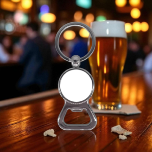 Beer glass on a bar counter with a metal bottle opener keychain in the foreground, featuring a circular white insert and ring handle.