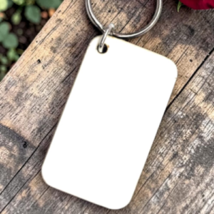 Blank white plastic name tag on a silver keyring lying on a weathered wooden surface.