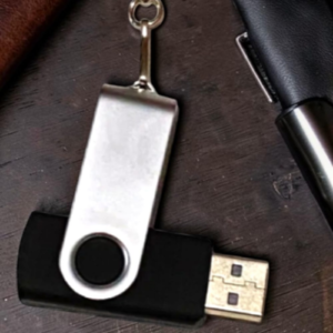 USB flash drive with a metal swivel cap on a dark wood table