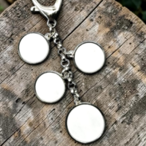 Keychain with four blank circular charms hanging from a metal chain on a weathered wooden surface.