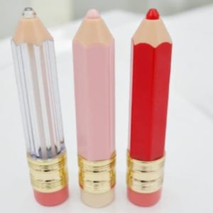 Three lip pencils in clear, pink, and red shades standing upright with gold ferrules, on a white background