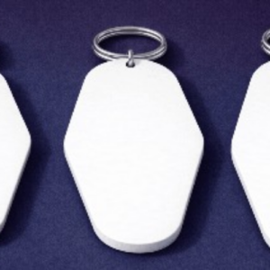 Three white blank plastic key tags with metal rings on a dark blue surface.
