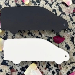 Two flat, car-shaped key fobs, one black and one white, resting on a speckled countertop with scattered flower petals.
