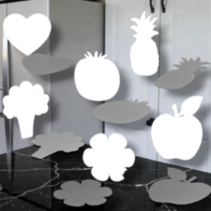 Assorted white and gray silhouettes of fruits, vegetables, and shapes hanging in a room (apple, pineapple, carrot, broccoli, heart, cloud).
