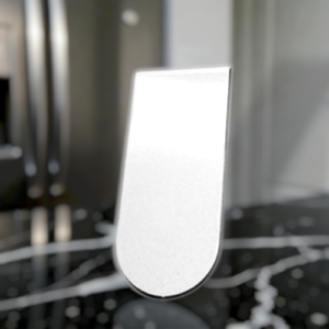 White curved metal object standing upright on a dark marble kitchen counter, with a blurred appliance background.